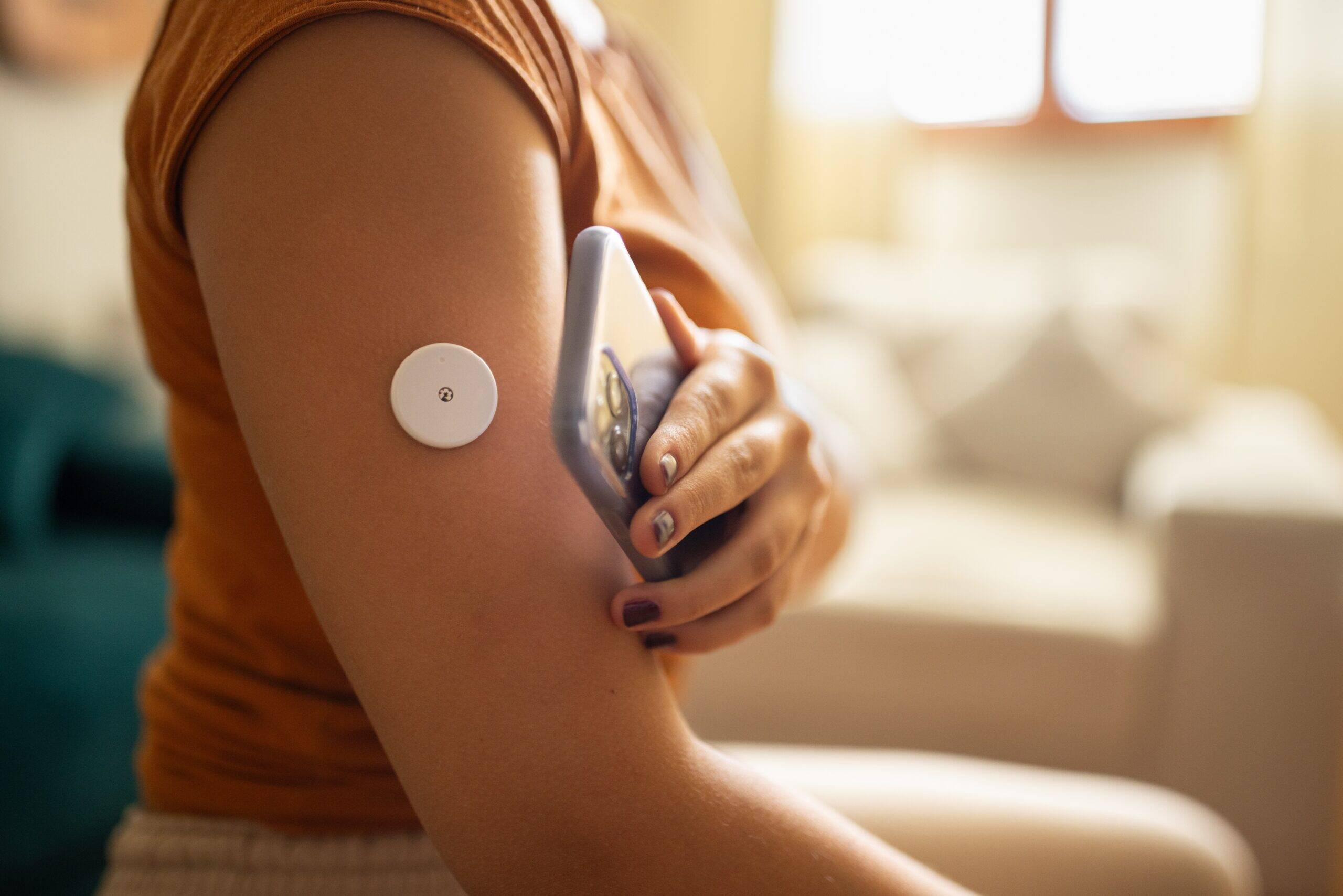 Woman's arm with circular blood sugar monitor on it